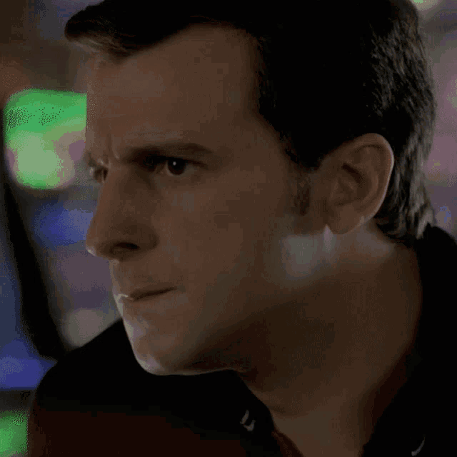 a close up of a man 's face with green lights in the background