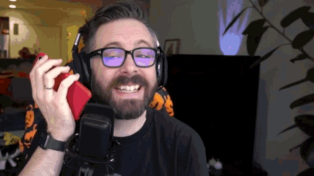a man wearing glasses and headphones is talking into a microphone and smiling