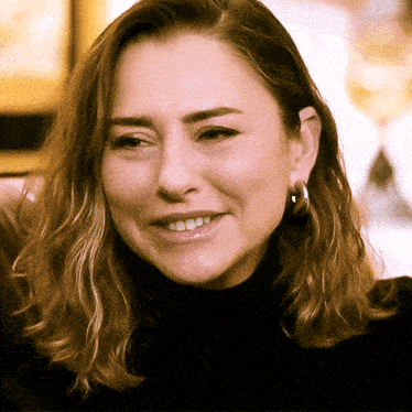 a woman wearing hoop earrings smiles for the camera