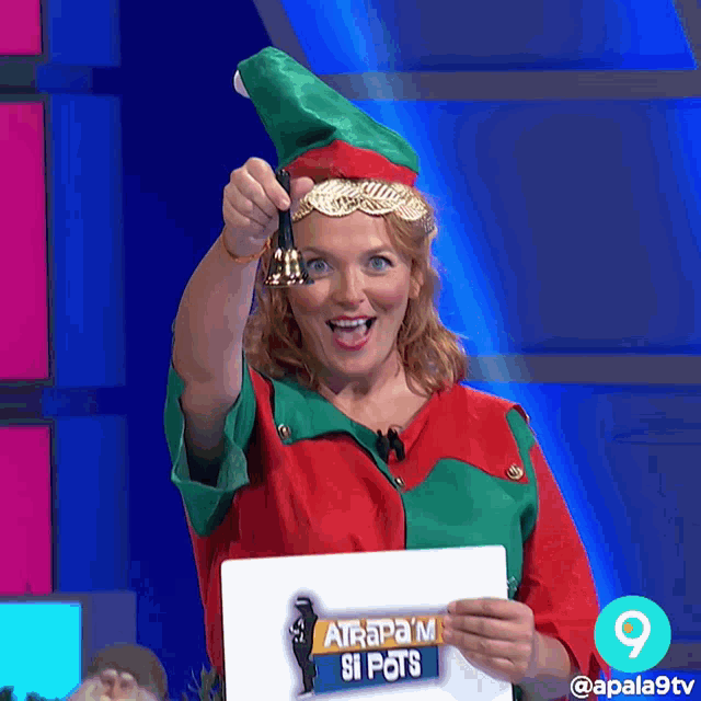 a woman dressed as an elf is holding a bell and a sign that says atrapam si pots