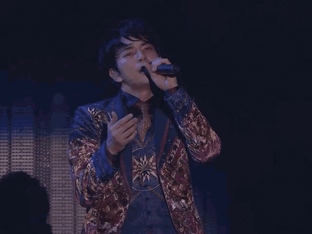 a man singing into a microphone with his hands up