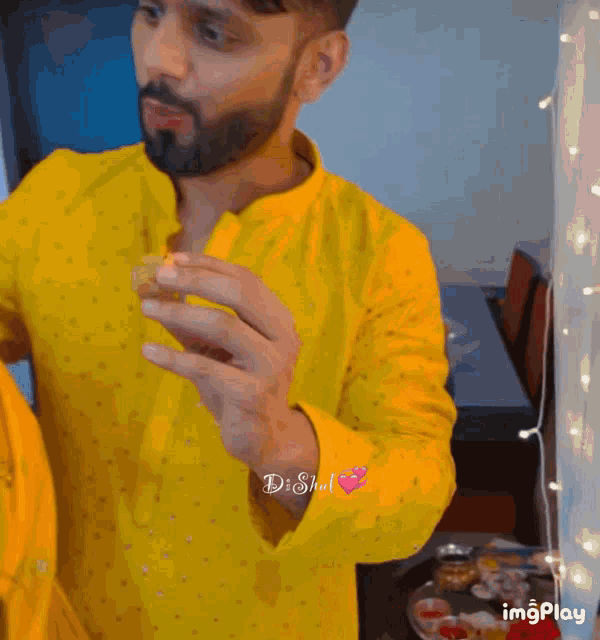 a man in a yellow shirt is feeding a woman a piece of fruit