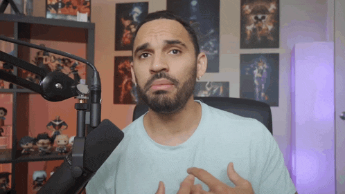 a man with a beard is sitting in front of a microphone and making a face
