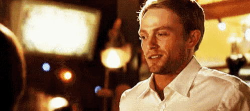 a man in a white shirt is smiling while standing in front of a woman .