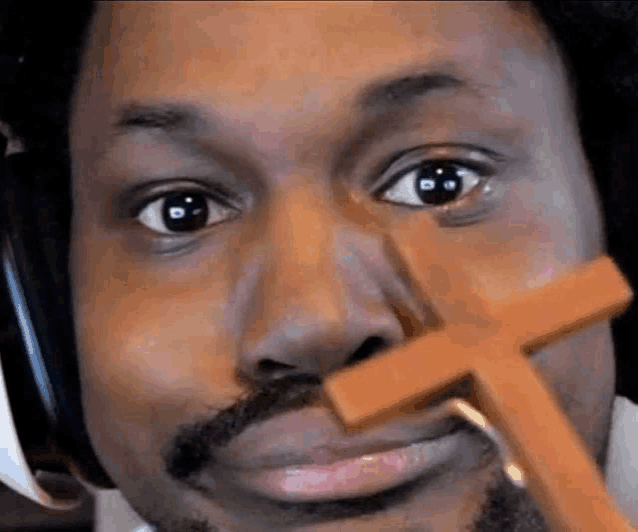 a man with a beard is holding a wooden cross in his mouth .