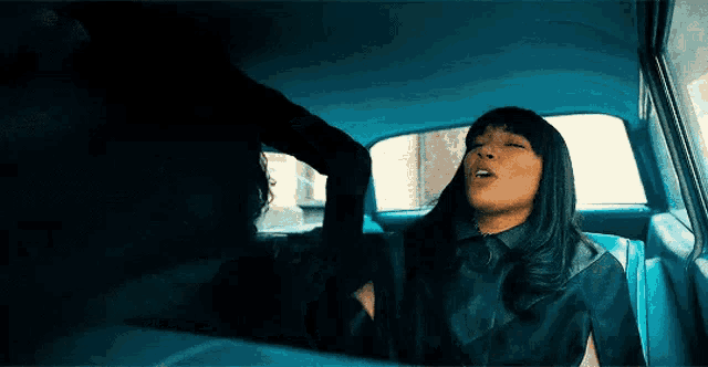 a woman is sitting in the back seat of a car with her eyes closed .