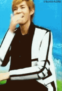 a man covering his mouth with his hand while wearing a black and white jacket