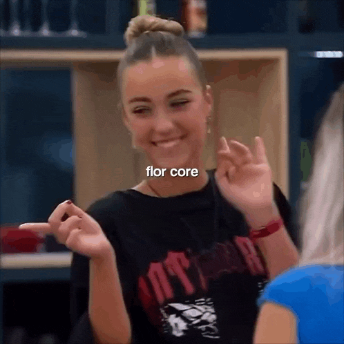 a girl is making a funny face and pointing at the camera while wearing a black shirt that says flor core .