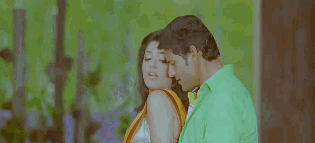 a man in a green shirt kisses a woman in a yellow dress