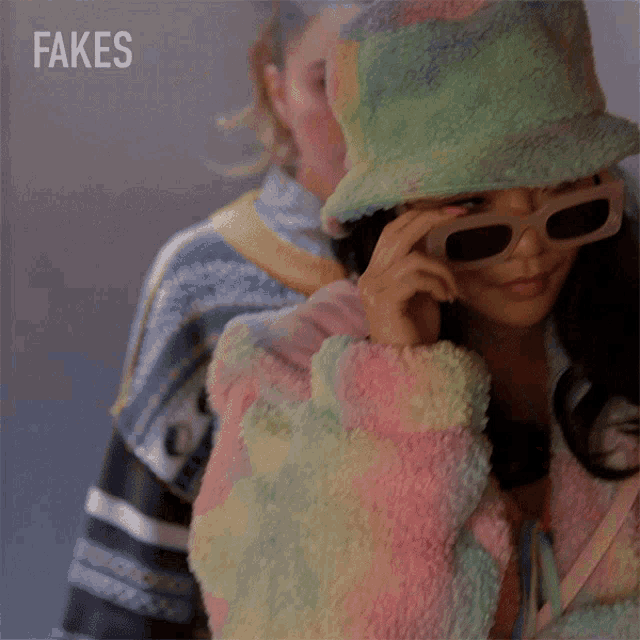 a woman wearing sunglasses and a hat with fakes written on the bottom right