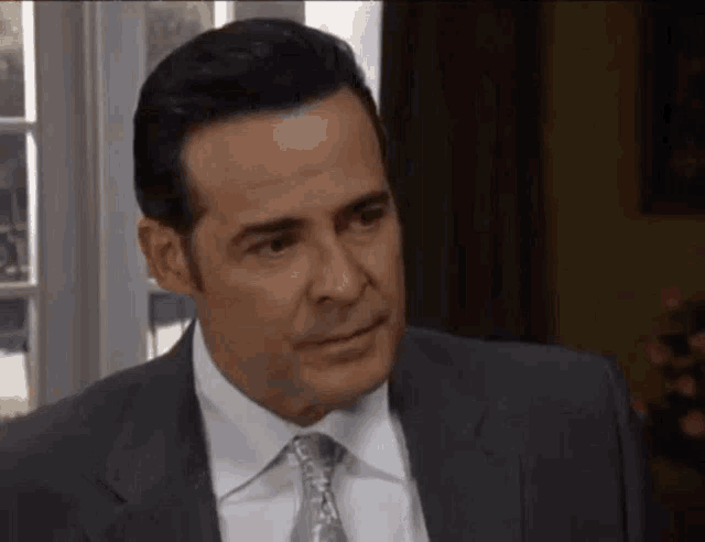 a man in a suit and tie is sitting in a room .