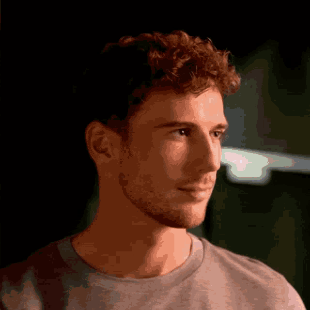 a man with curly hair wearing a grey shirt