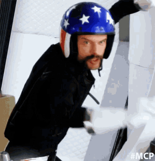 a man with a beard wearing a helmet and gloves is holding a roll of toilet paper .