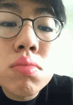a young man wearing glasses and a hat is making a face .