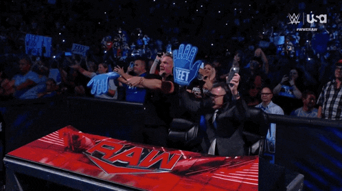 a crowd of people watching a wrestling match with the word raw on a red table