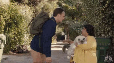 a man with a backpack is standing next to a woman holding a poodle .