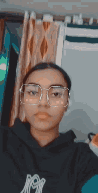 a girl wearing glasses and a black shirt with the letter n on it