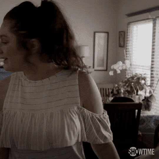 a woman in a white off the shoulder top is standing in a room with showtime written on the bottom of the screen