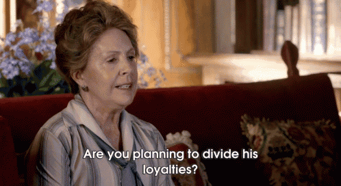 an elderly woman is sitting on a red couch and talking to someone and the words are you planning to divide his loyalties