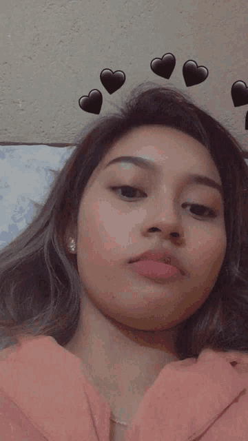 a girl with three black hearts on her head looks at the camera