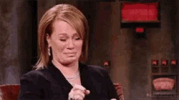 a woman is laughing while sitting in a chair in front of a red light .
