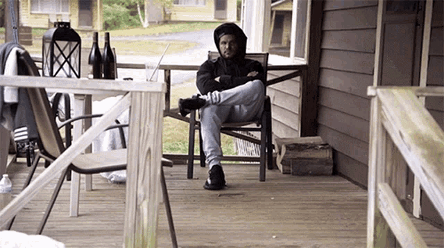 a man sits on a porch with his feet crossed