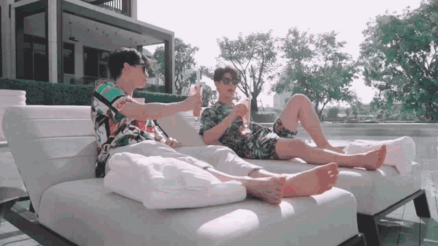 two men laying on a couch with their legs crossed
