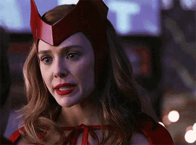 a close up of a woman wearing a red cape and helmet .