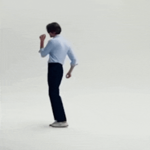 a man in a blue shirt and black pants is dancing on a white surface .