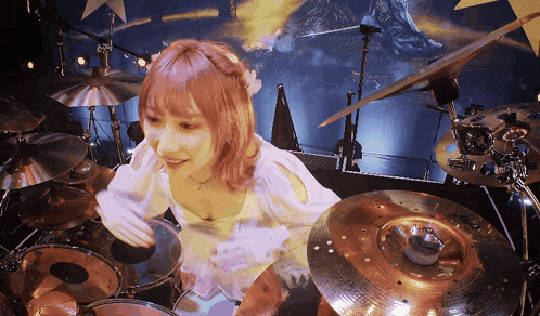 a woman with pink hair is playing drums on stage
