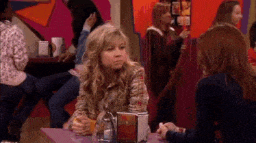a girl is sitting at a table in a restaurant with other girls .