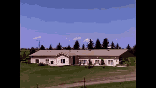 a large house sits in the middle of a grassy field surrounded by trees