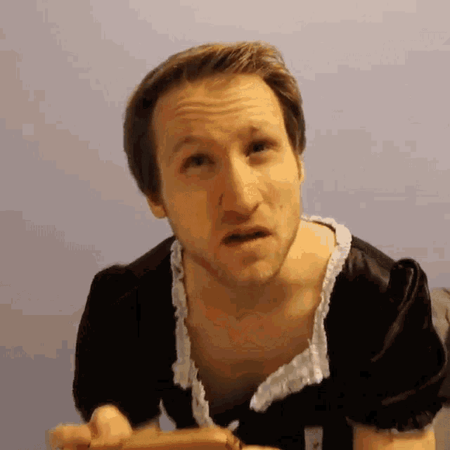 a man in a maid costume looks at the camera