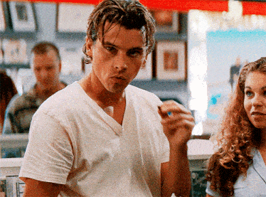 a man in a white t-shirt is talking to a woman