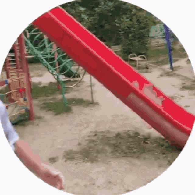 a red slide in a circle with a person standing in front of it