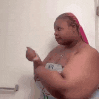 a woman wrapped in a towel is standing in front of a mirror in a bathroom .