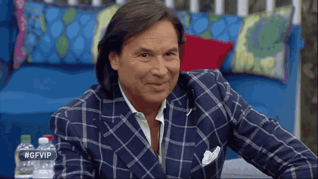 a man in a blue and white plaid suit is sitting on a couch