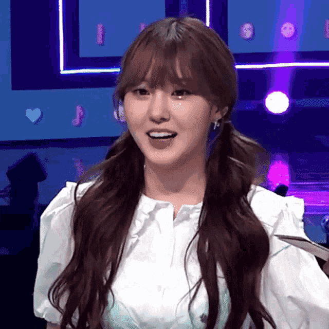 a woman with pigtails and a white shirt is smiling .