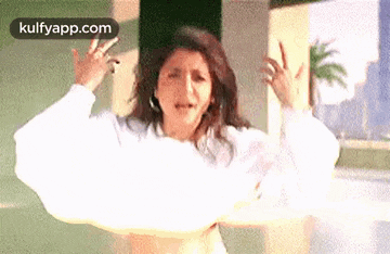 a woman in a white shirt is dancing in front of a building .