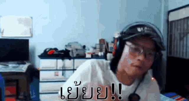 a man wearing headphones and glasses is sitting in front of a computer screen .