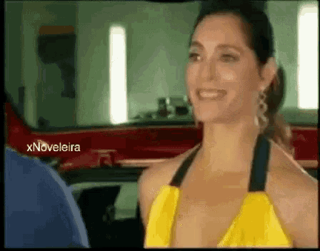 a woman in a yellow dress is smiling in front of a car