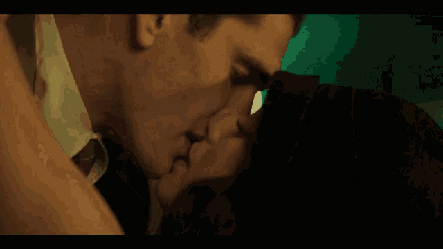 a man and a woman are kissing in a dark room in a movie .