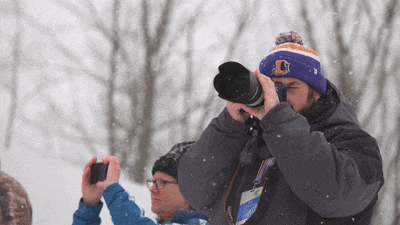 a man wearing a purple hat with the letter l on it takes a picture in the snow