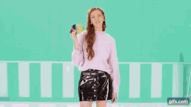 a woman is holding four credit cards in her hand .
