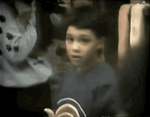 a young boy in a blue shirt is looking at something in a dark room .