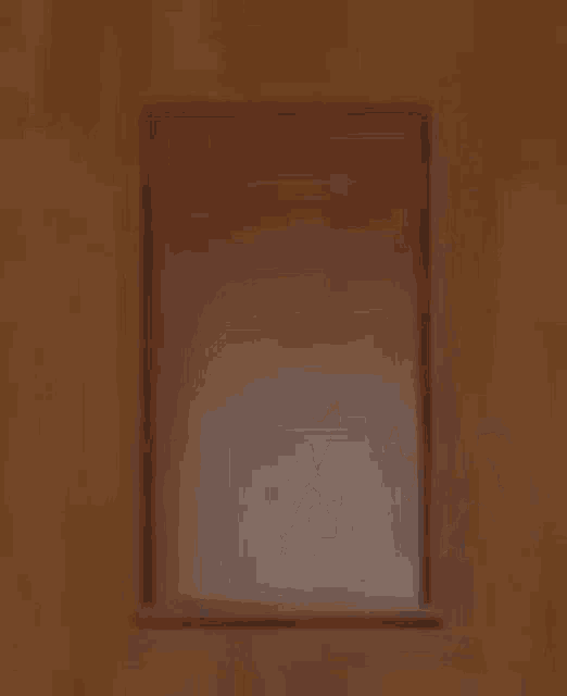 a boy wearing glasses is peeking out from behind a wall .