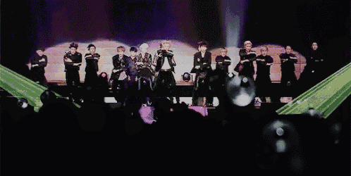 a group of people standing on a stage with their arms crossed and a man singing into a microphone