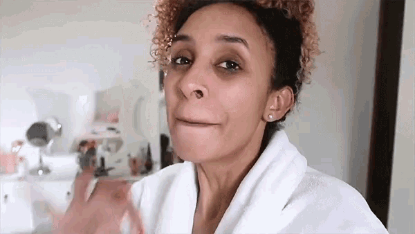 a woman with curly hair wearing a white robe is making a funny face