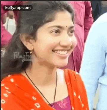 a woman in a red dress is smiling in a crowd .