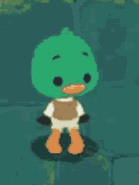 a green duck with orange feet and a white shirt is standing on a rock .